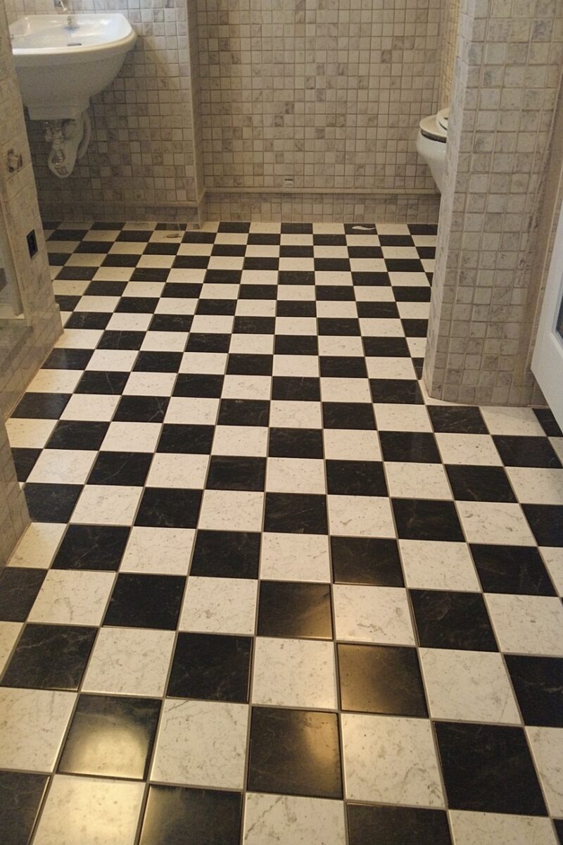 Classic black and white marble checkerboard tile floor in an elegant bathroom with mosaic wall tiles