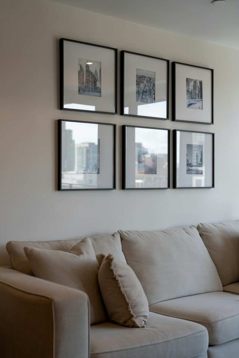 A gallery wall of six black framed prints above a light gray sofa in a living room