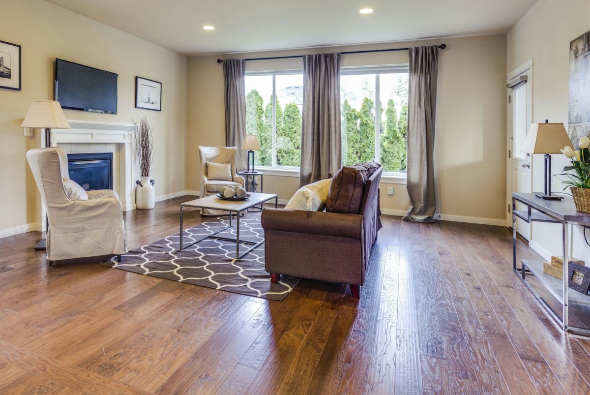 A bright living room where a small gray trellis rug sits only under the coffee table, with the sofa and chairs off it