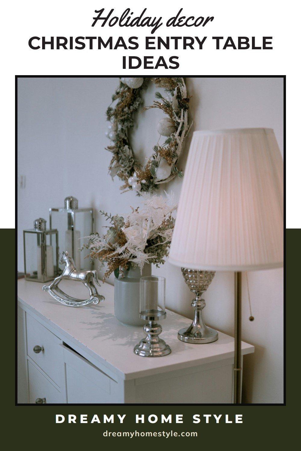 Christmas Entry Table Ideas: A white dresser styled for Christmas with a frosted wreath on the wall, silver lanterns, a vase of white dried stems and a lamp with a pleated shade