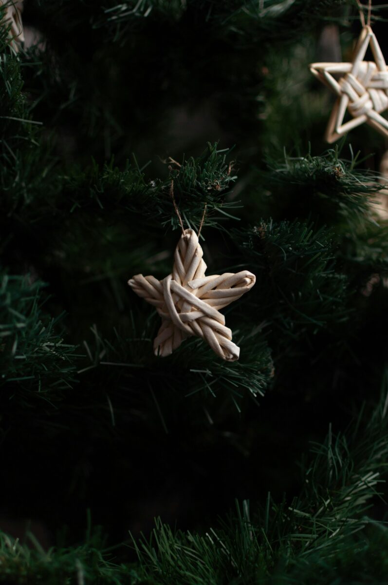 Woven straw stars hanging on twine from the branches of a Christmas tree