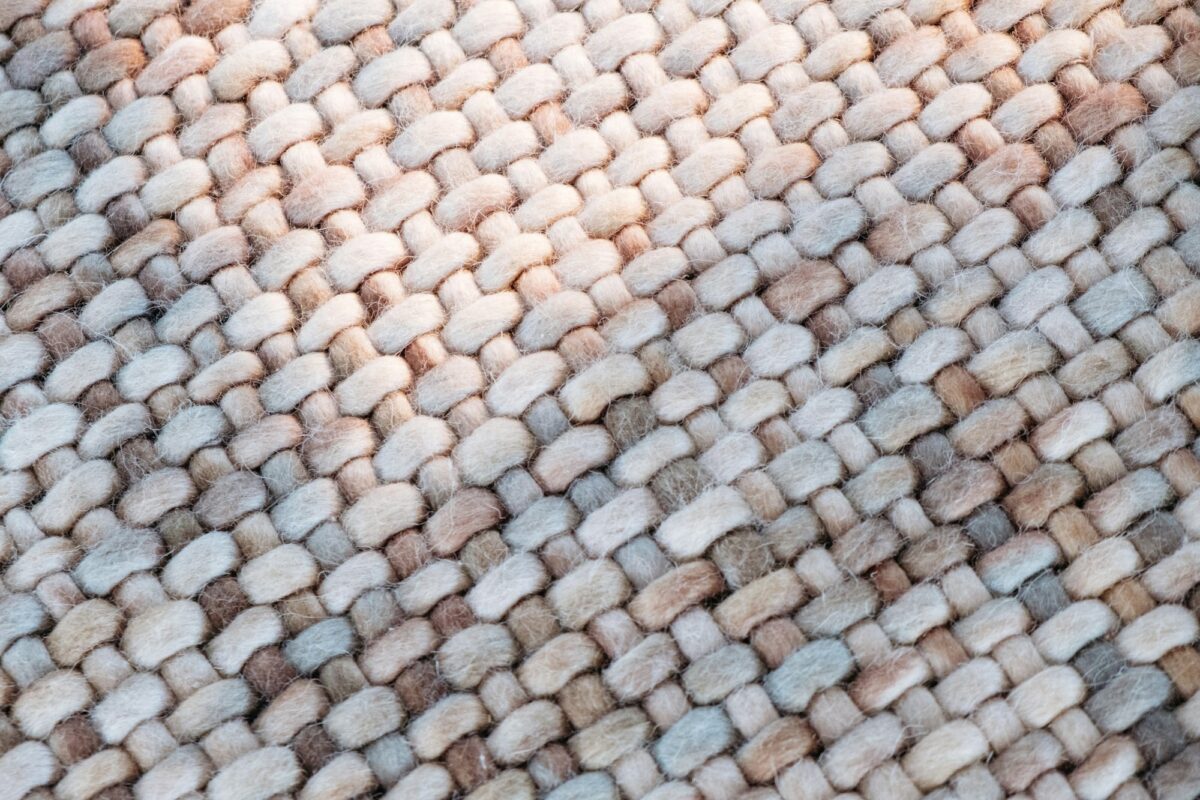 Close-up of a chunky woven rug with fuzzy loops in cream, brown and gray-blue