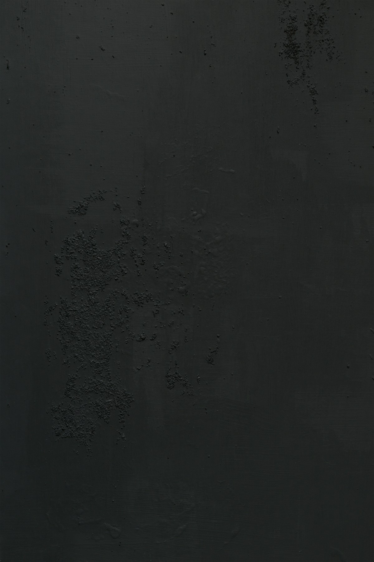 Close-up of a matte dark gray wall with rough patches and bumps in its surface
